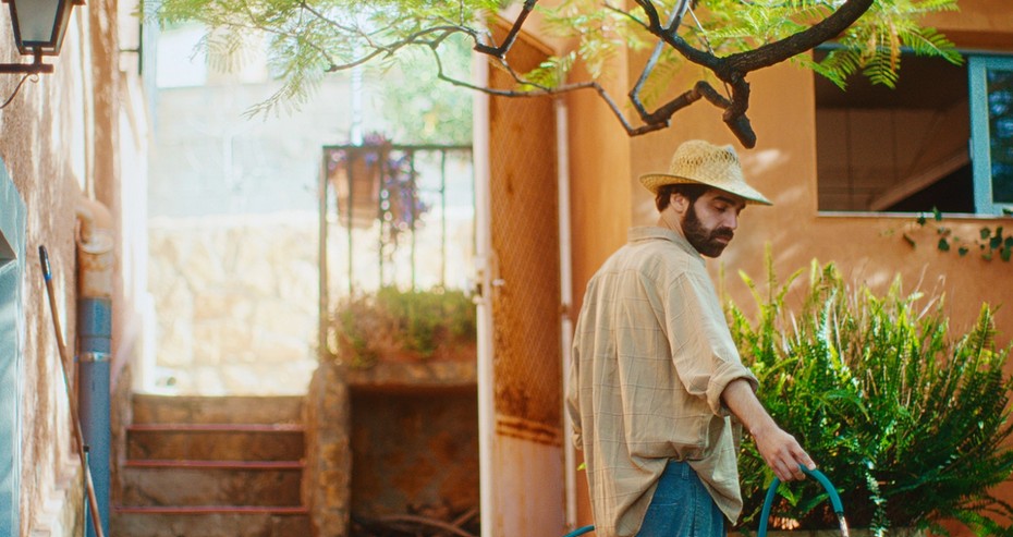 Señor con sombrero regando plantas