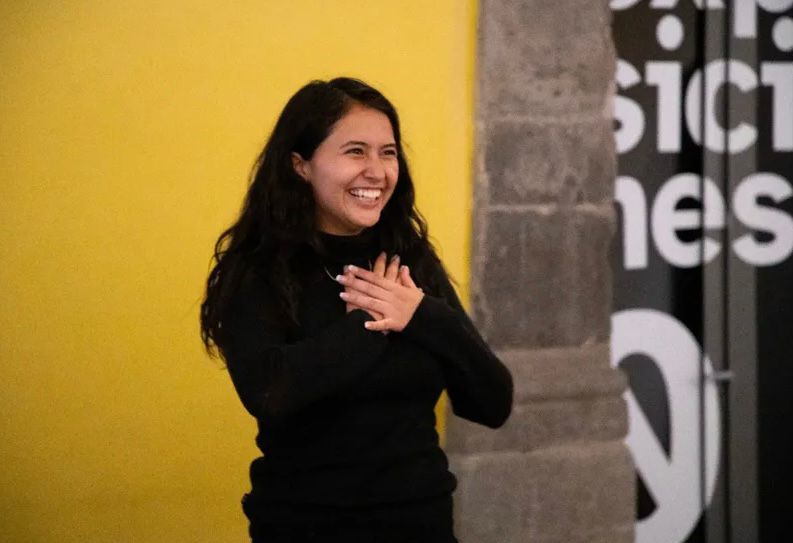Mujer sonrie haciendo una seña de LSM